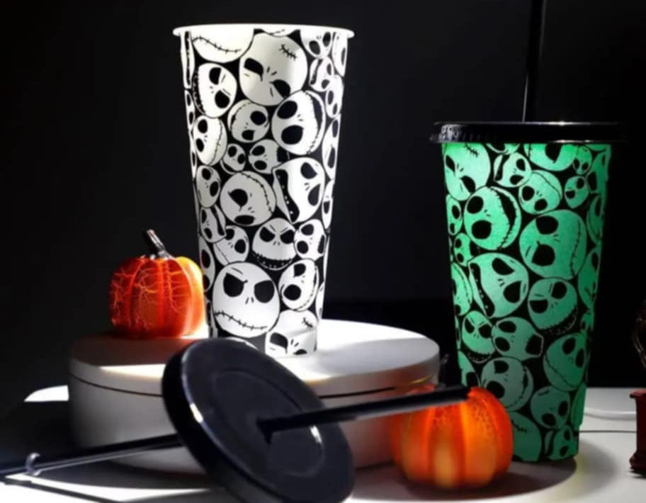 Two Halloween-themed tumblers with pumpkins on a dark background